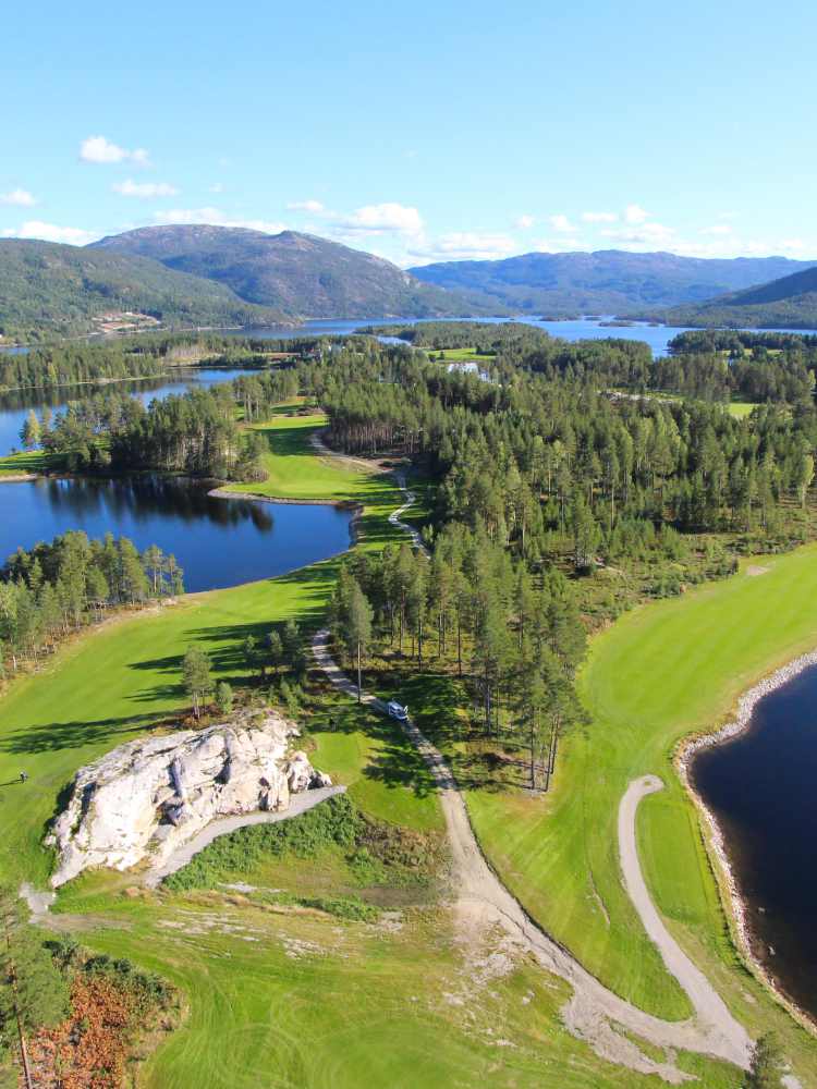 A stunning aerial view of Vrådal Golf Course, embraced by multiple lakes, featuring clear blue waters, vibrant greenery, and perfect weather.
