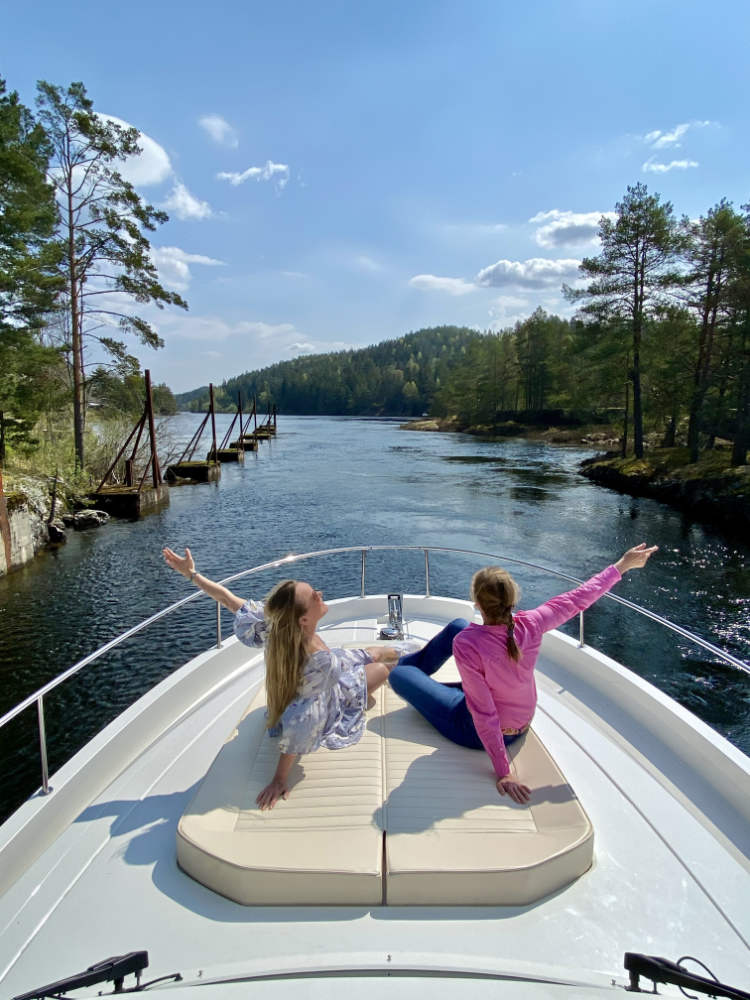 wo women enjoying a boat ride on a sunny day in Norway, surrounded by serene lake and scenic beauty.