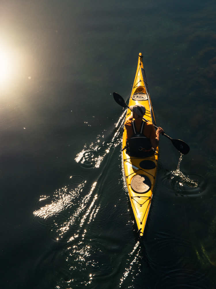 Aerial view of a yellow canoe on serene, glassy water.
