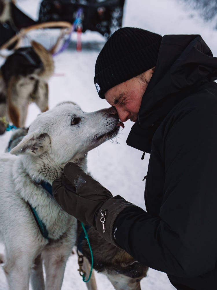 Heartwarming image of Jonas receiving affectionate licks from Haukeli Huskies, showcasing the bond between man and husky.