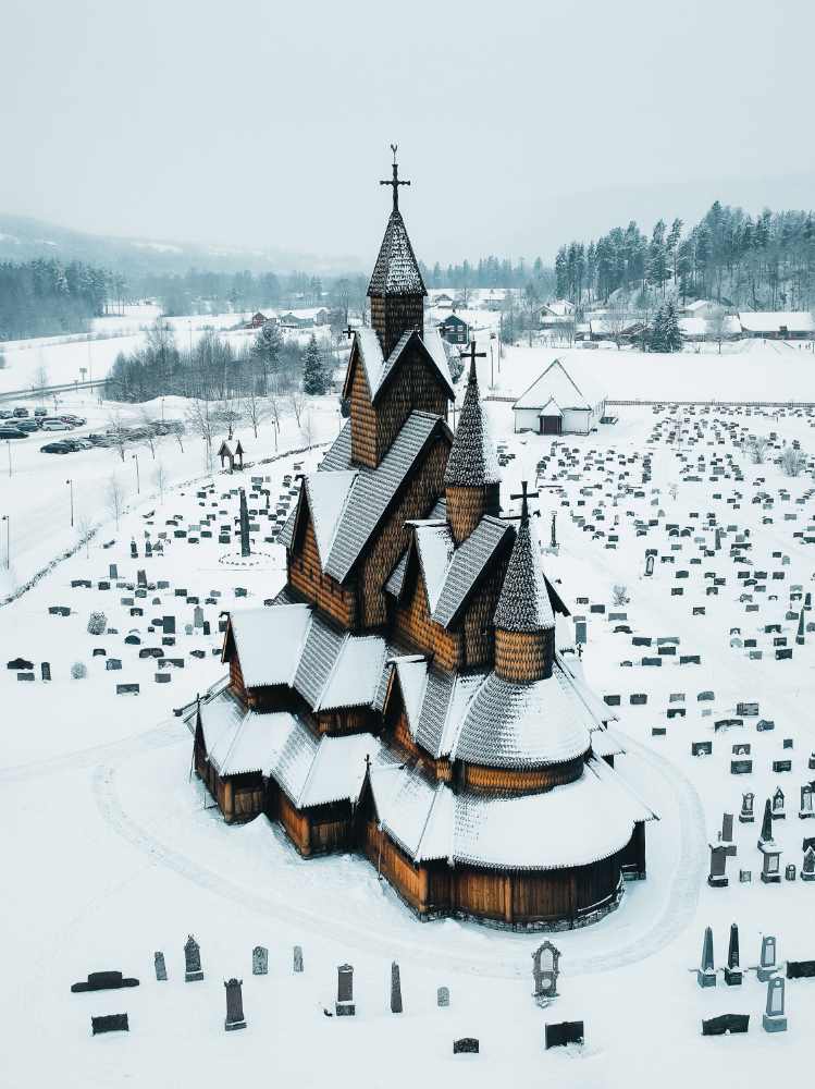 Heddal Stave Church in winter, covered in snow, offering a serene and enchanting view of seasonal beauty.