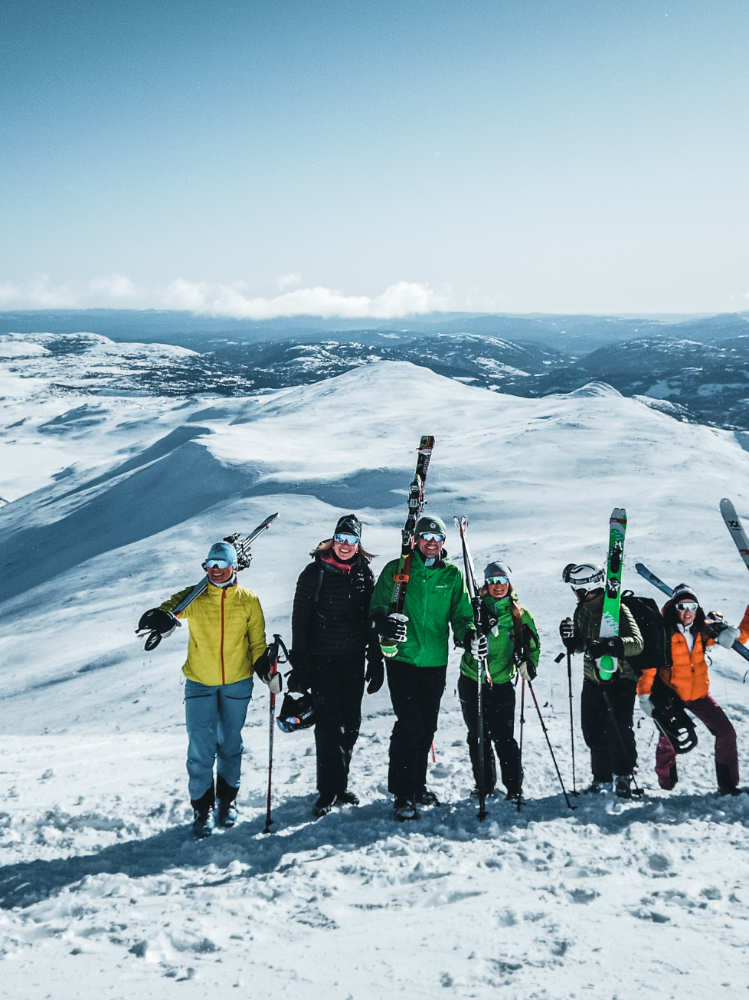 Skiers posing for a group photo with skis on their shoulders, set against a scenic snowscape, capturing the camaraderie of winter sports.