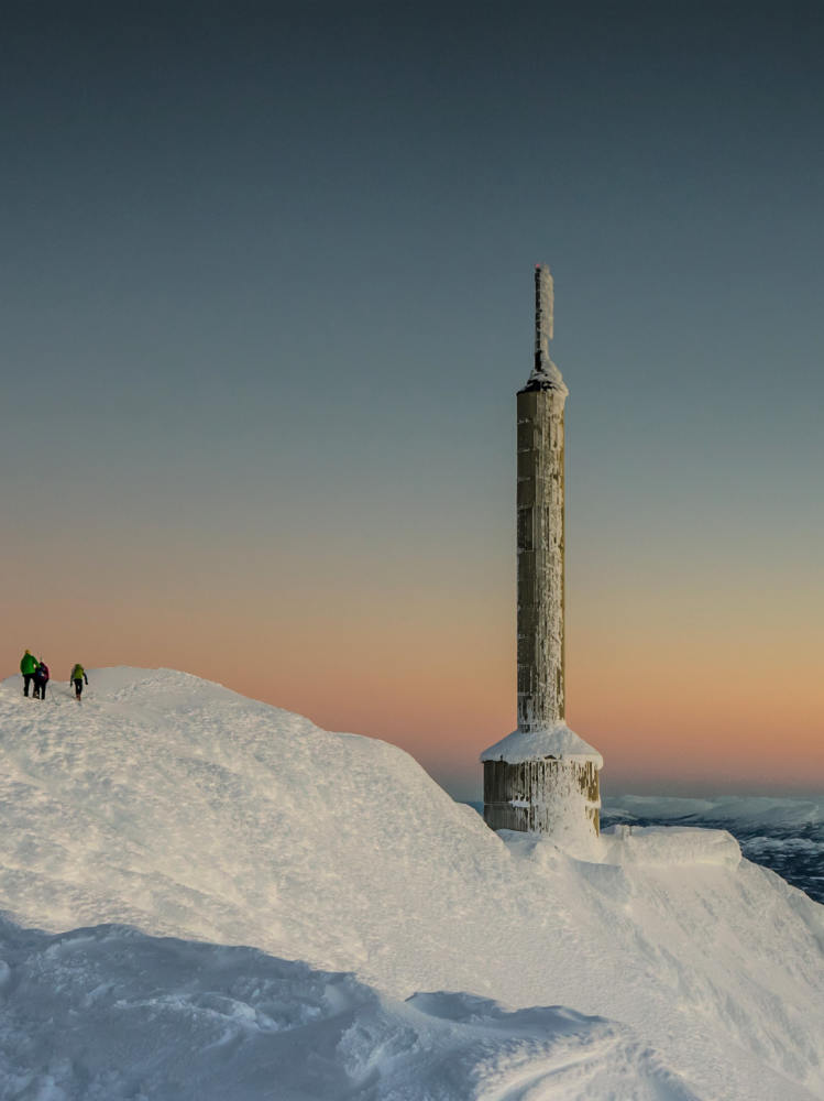 Scenic view of the radio tower at Gausta Skisenter with a sunset and snow-capped mountain in the background, offering a breathtaking panorama.
