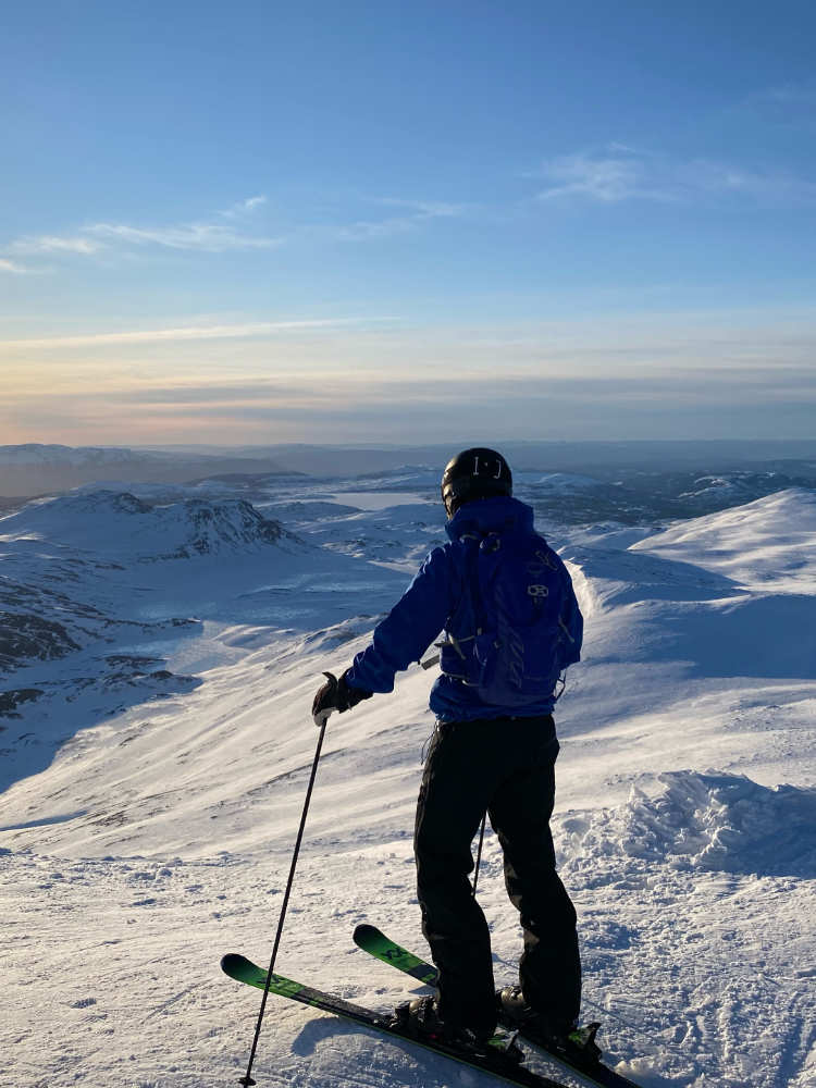 Skier in a blue jacket enjoying a thrilling skiing experience at Gausta Skisenter, highlighting the adventure and beauty of the ski area.