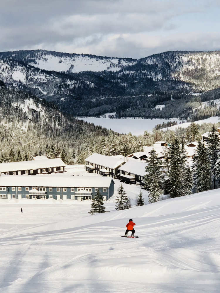Snowboarder descending a ski slope with houses in the background